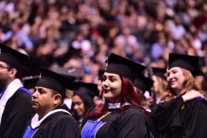 focus on female student in crowd surrounded by classmates at graduation