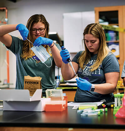 Two forensic science students analyze DNA and crime scene evidence