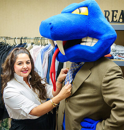 Lisa Ann Garcia helps Rattlerman fix his tie at the Rattler Wardrobe in the Greehey School of Business.