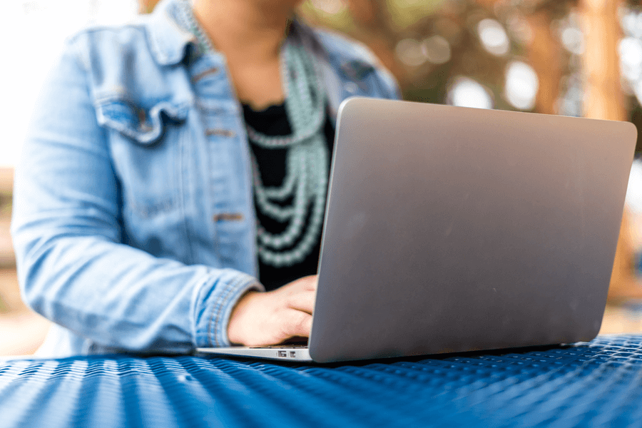 Student on laptop without face showing on campus.