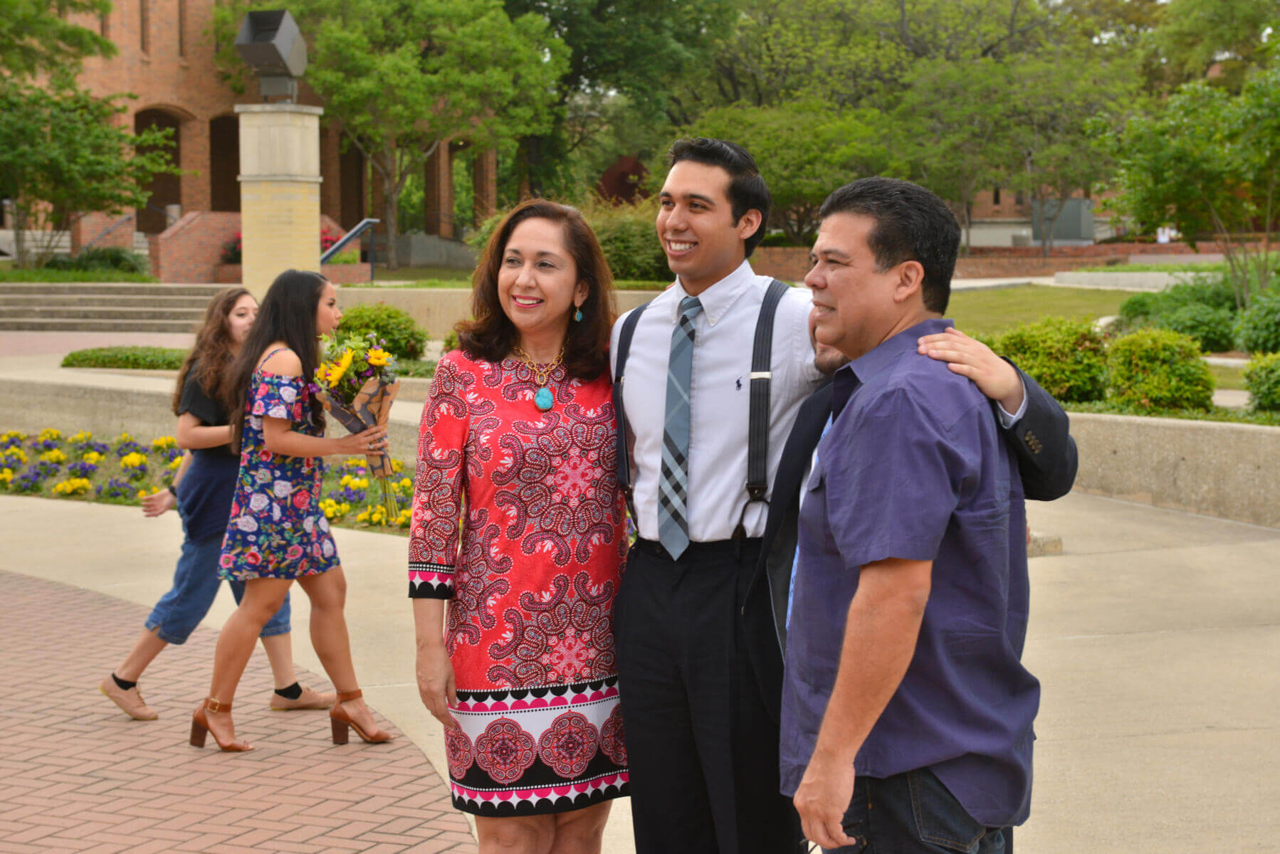 Parents standing outside with their student posing for a photo