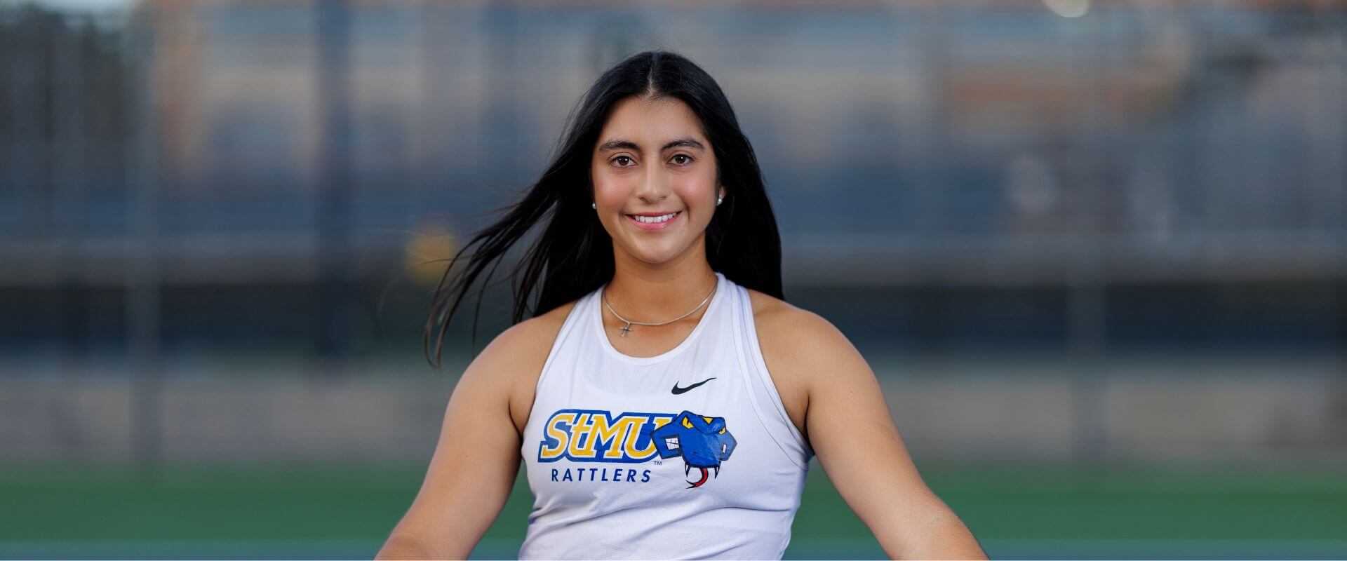 Stela Sifuentes stands behind a tennis net.